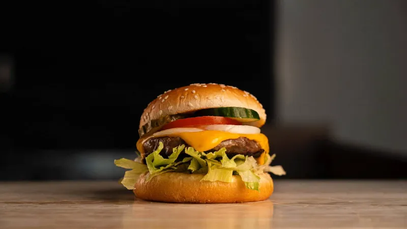 Cheeseburger met sla, tomaat, ui, augurk en gesmolten kaas